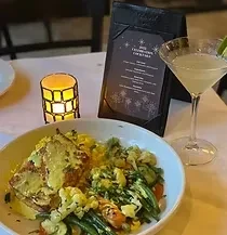 Fillet with green sauce, rice, vegetables, cocktail on white tablecloth.