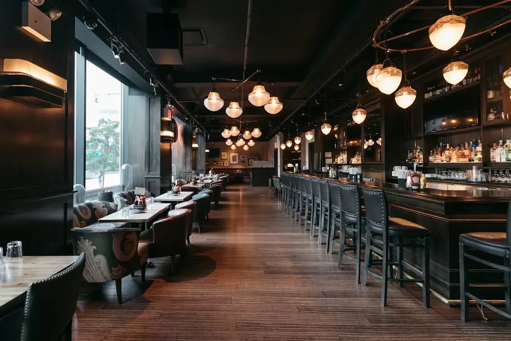 Dimly lit, upscale restaurant interior with bar, tables, and warm lighting.