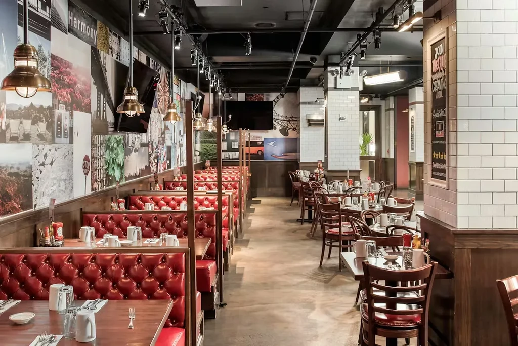Modern, empty restaurant interior with red booths, tables, and eclectic decor.