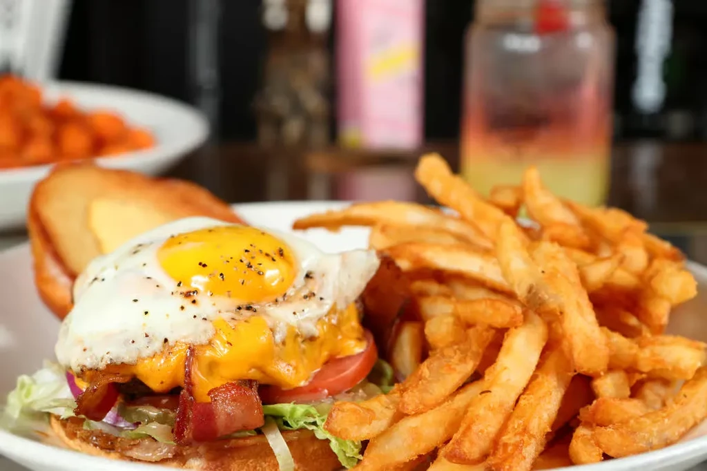 Gourmet burger with a sunny-side-up egg, bacon, cheese, and fries.