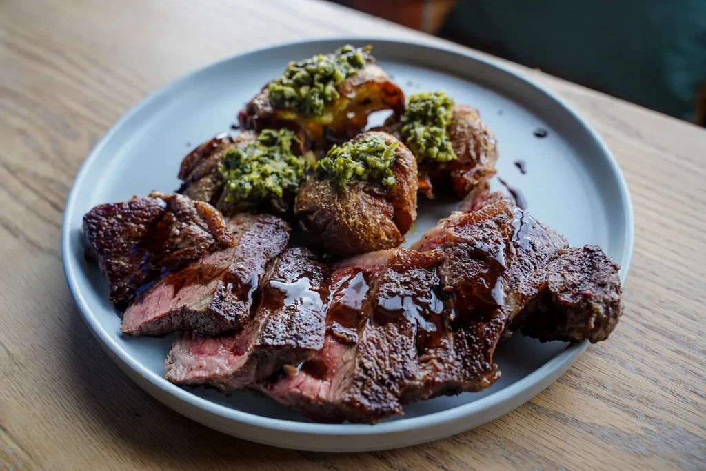 Medium-rare steak, roasted potatoes, and green sauce.