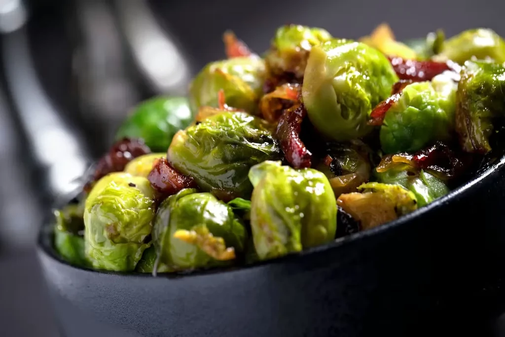 Roasted Brussels sprouts with reddish-brown pieces in a dark bowl.