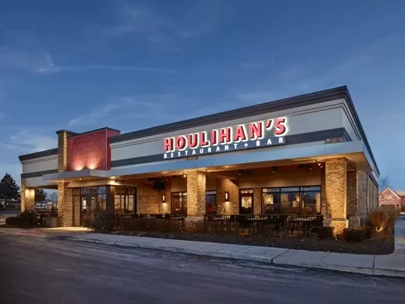 Modern Houlihan's Restaurant + Bar building exterior, warmly lit at dusk.