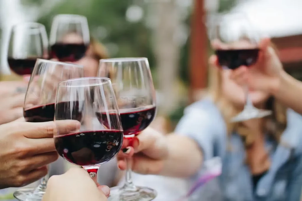 Close-up of multiple hands holding red wine glasses in a toast.