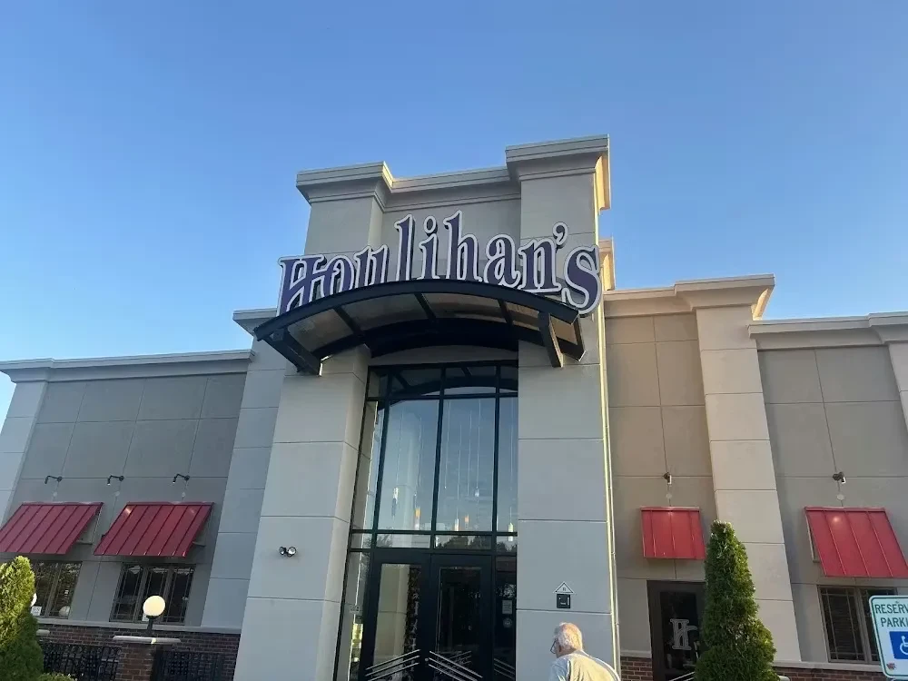 Exterior of modern Houlihan's restaurant with grey facade and red awnings.