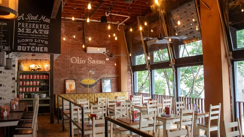 Industrial-chic restaurant with exposed brick, a butcher sign, and wooden tables.