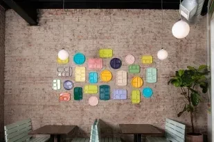 Colorful dish art on a rustic brick wall in an empty cafe.
