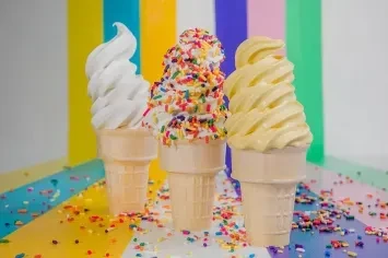 Three soft-serve waffle cones with vanilla, sprinkles, and yellow.