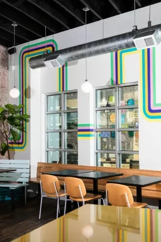 Modern restaurant interior with striped walls, industrial ceiling, and varied seating.