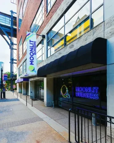 Moonlit Burgers restaurant facade, urban setting, with colorful signs.