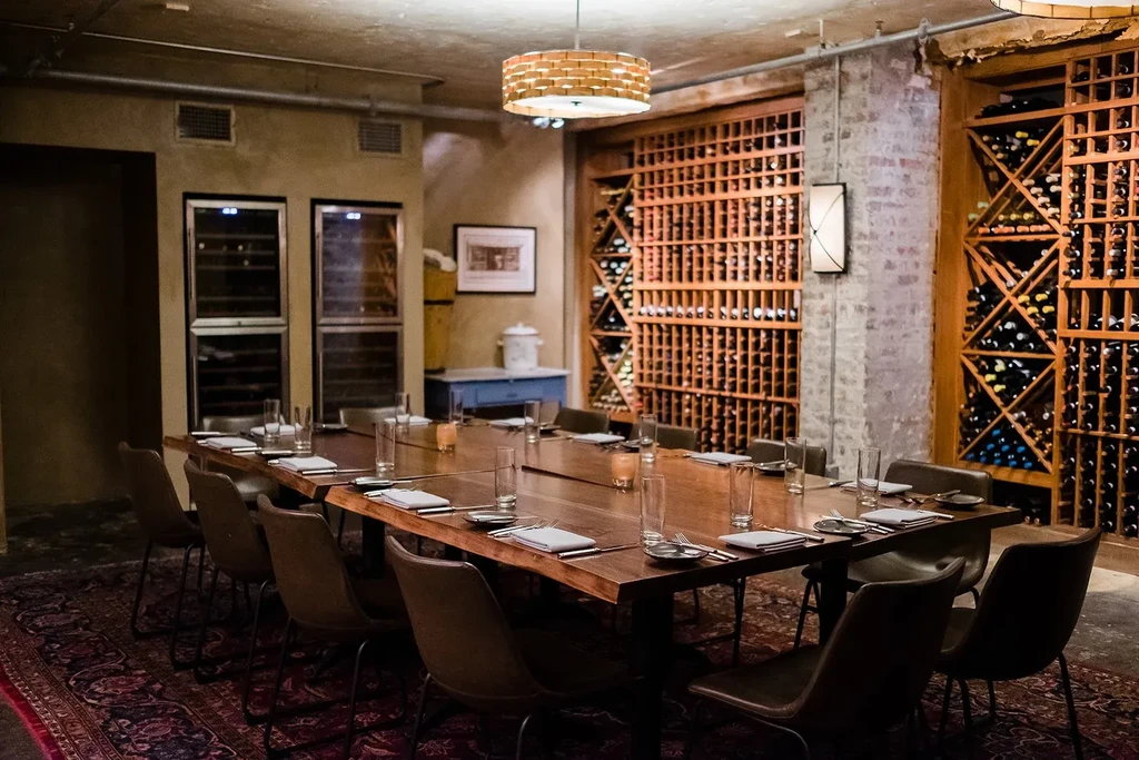A long set dining table in a private room with extensive wine storage.