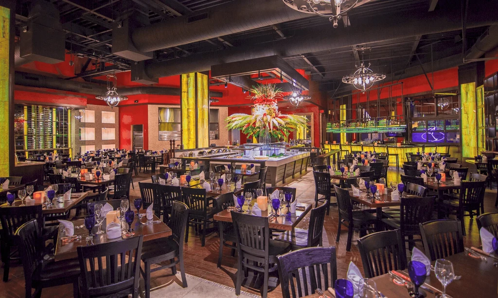 Upscale restaurant with red walls, elaborate floral display, and modern bar.
