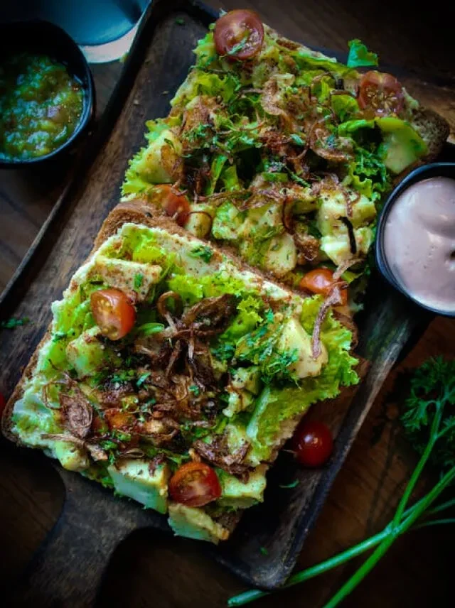 Avocado toast with tomatoes, crispy onions, fresh herbs, and two dips.