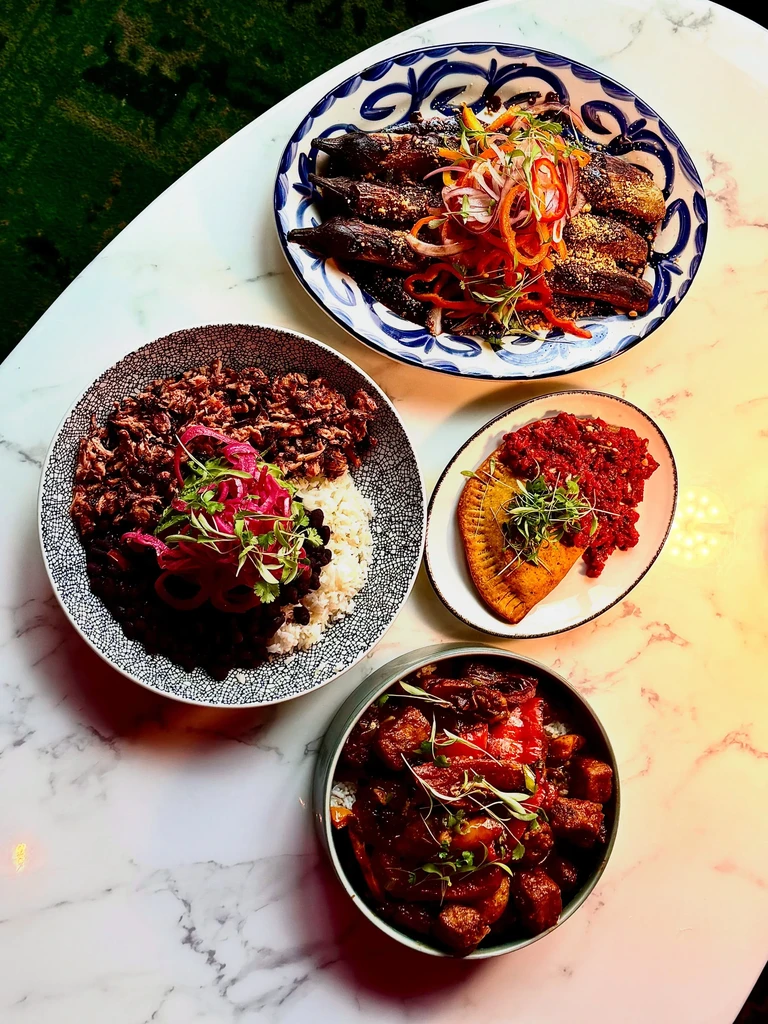 Vibrantly plated fish, rice, pastry, and stew on a marble table.