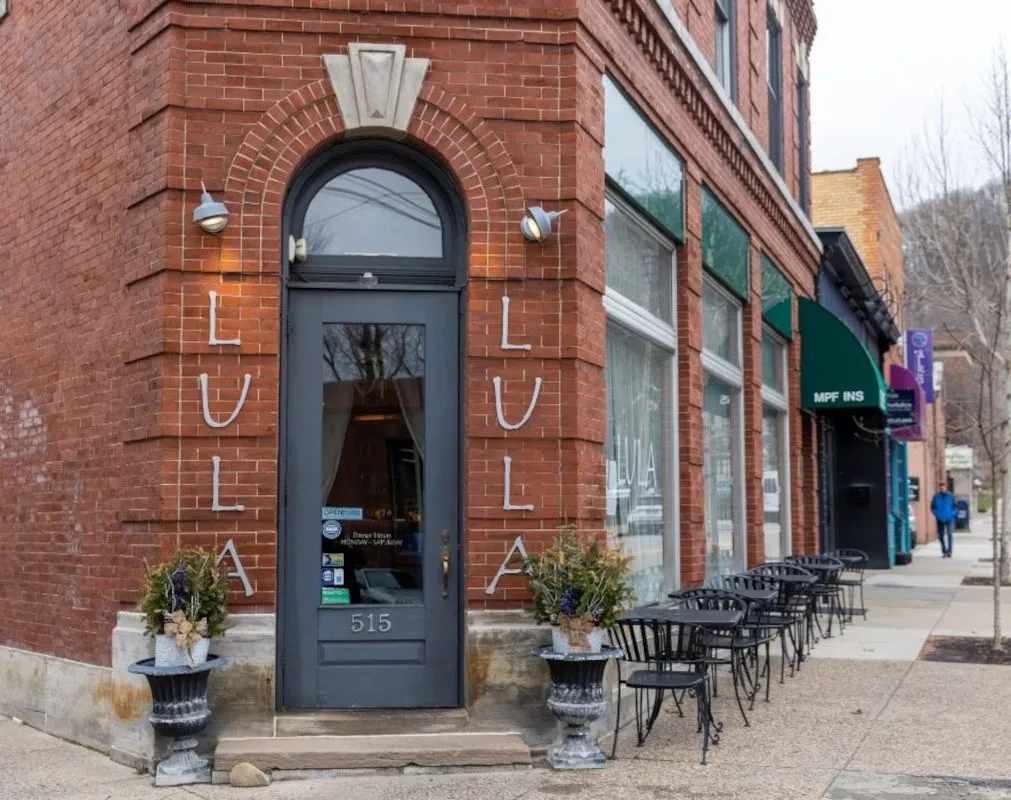 LULA, a brick building with an arched entrance and outdoor seating.
