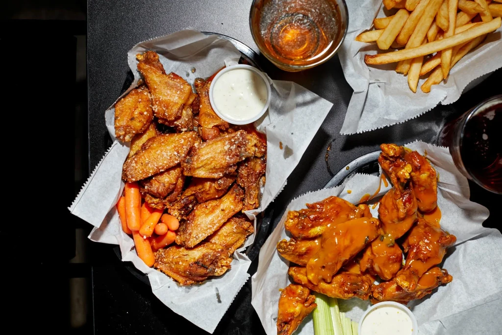 Overhead: Crispy and sauced chicken wings, fries, and two drinks.