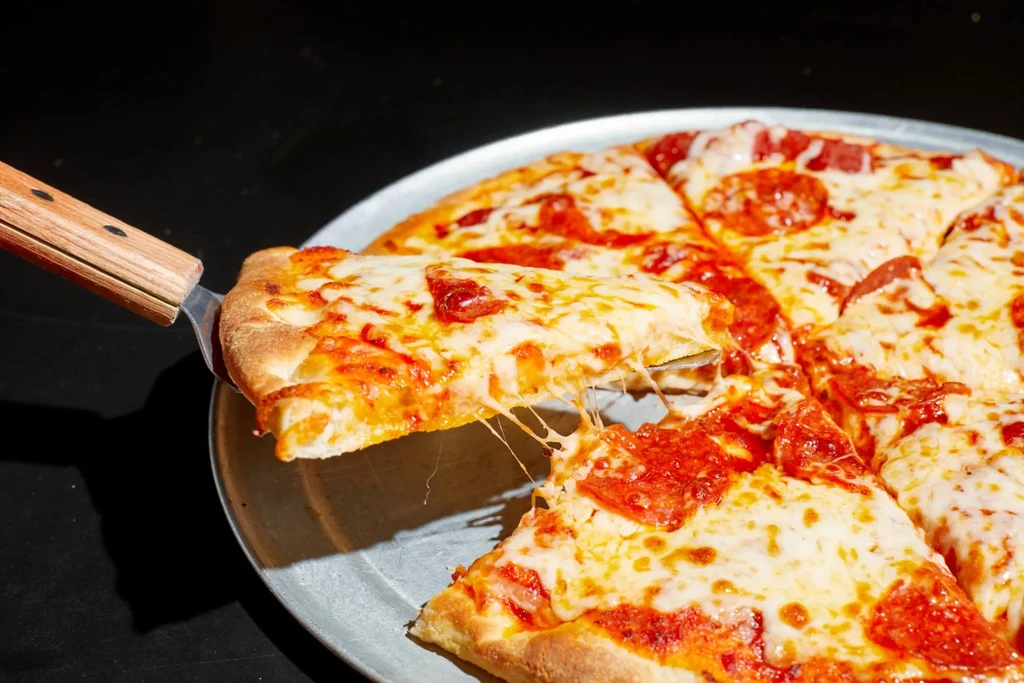 Pepperoni pizza with a slice being lifted, showing stretchy cheese.