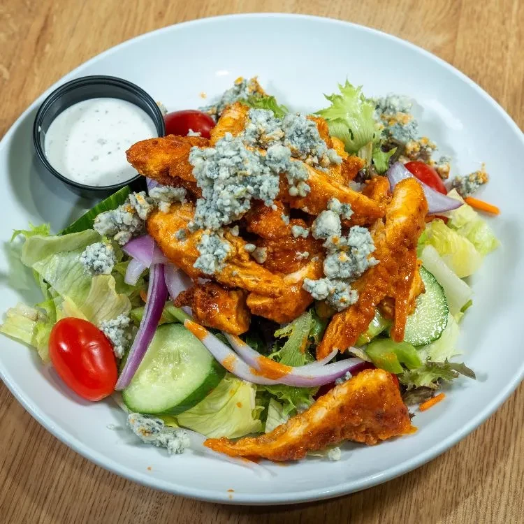 Top-down buffalo chicken salad with blue cheese, vegetables, and creamy dressing.