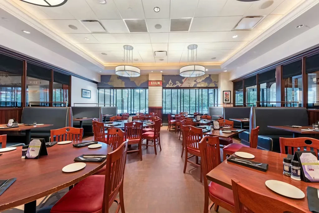 Empty restaurant dining room with booths, wooden tables, and map mural.