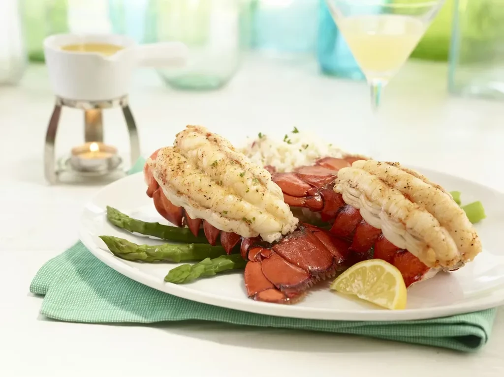 Grilled lobster tails with pulled meat, asparagus, rice, and lemon.