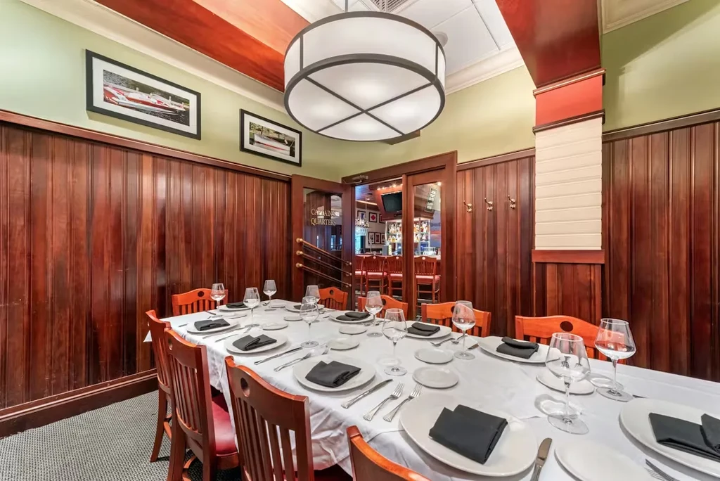 Formal dining room with long set table and dark wood paneling.