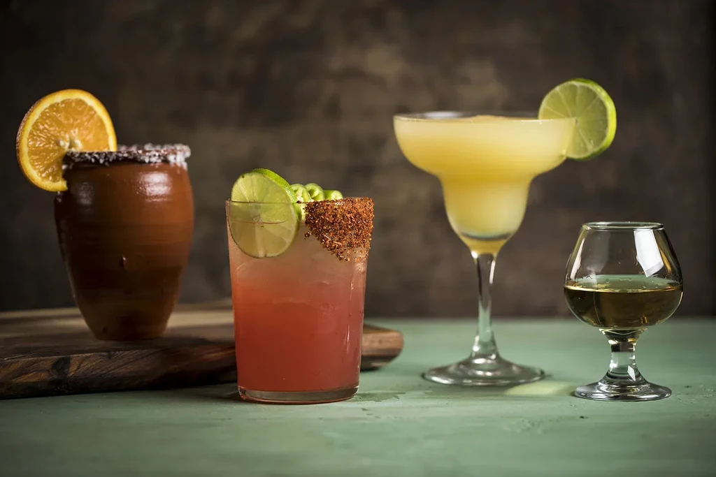 Still life: Four alcoholic beverages on a rustic table with a moody backdrop.