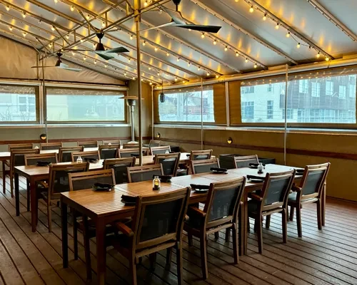 Empty rooftop dining area with wooden furniture and string lights.