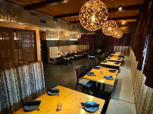 Warm, empty restaurant interior with wooden tables and spherical pendant lights.