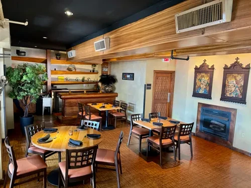 Restaurant interior featuring tables, bar, fireplace, and colorful figure artworks.
