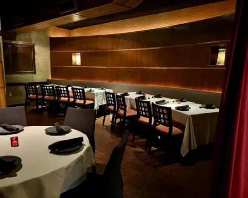 Dimly lit upscale restaurant with elegant tables and curved wood paneling.
