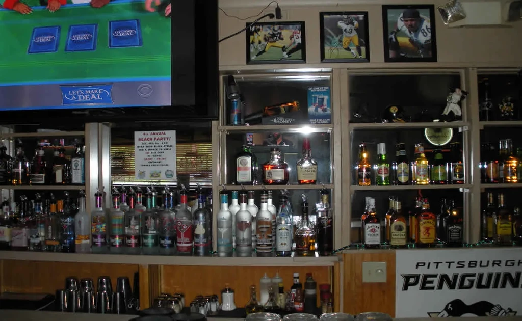 Well-stocked bar, TV displays 'Let's Make a Deal,' with sports decorations.