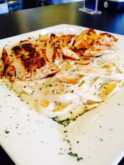 Plate of creamy pasta with sliced grilled chicken.