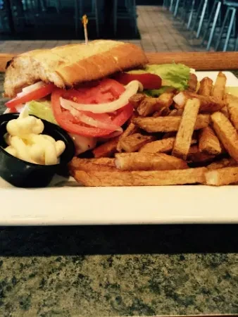 A large sub sandwich, french fries, and white sauce on a plate.