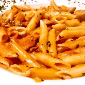 Penne pasta with creamy orange sauce, meat, mushrooms, and herbs.