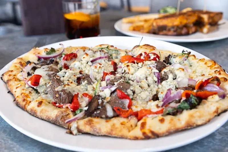 Gourmet pizza with steak, blue cheese, red onion, and bell peppers.