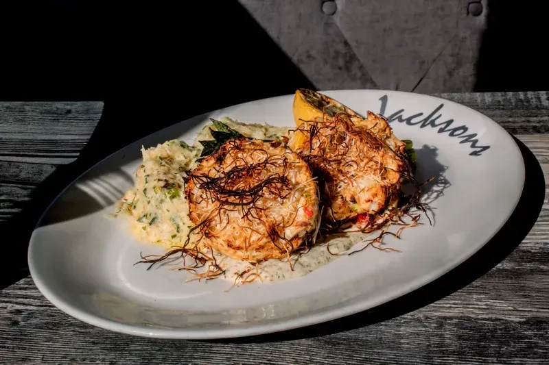 Jackson's two crab cakes with crispy topping, creamy side, and lemon.