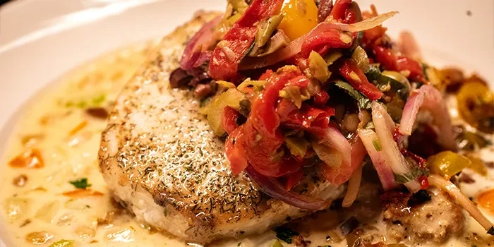 Herb-crusted fish or poultry, creamy sauce, diced vegetables, colorful salsa.