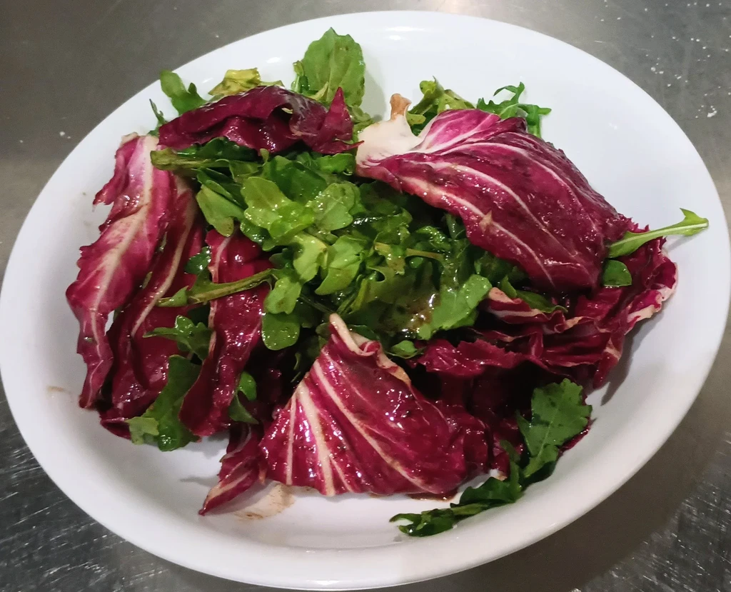 Close-up of radicchio and arugula salad in a white bowl.