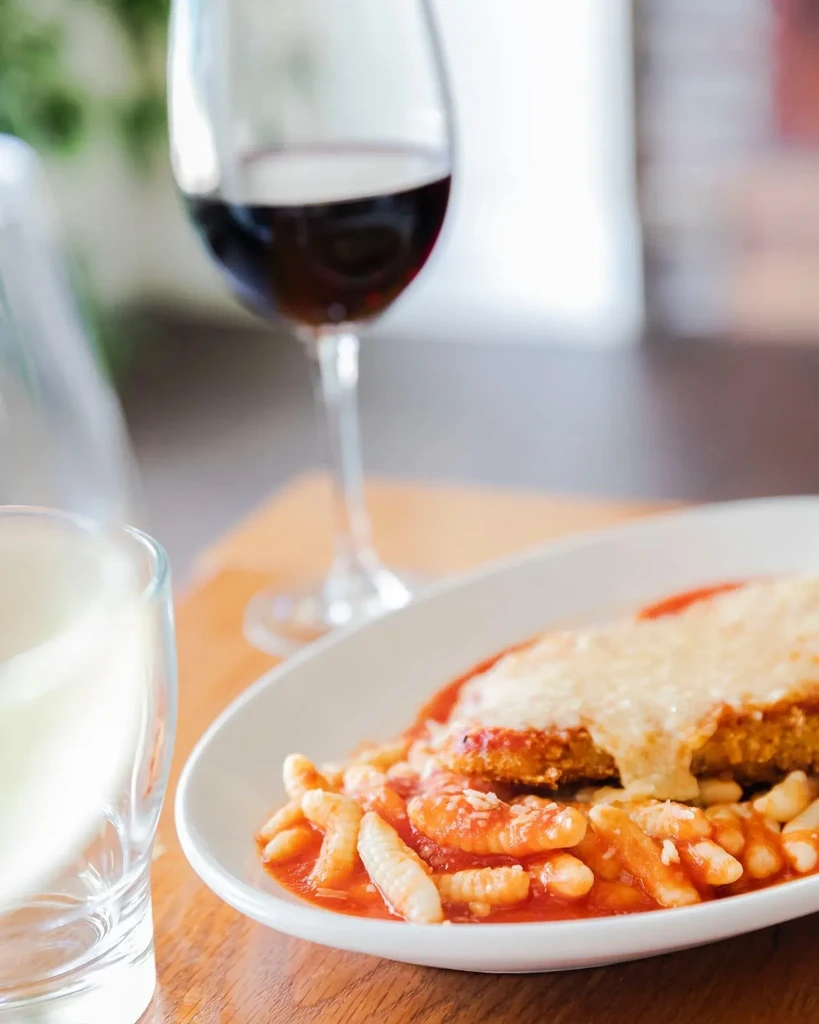 Breaded cutlet with melted cheese, pasta in sauce, and red wine.