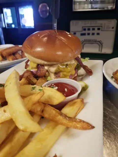 Close-up of a large burger with bacon, melted cheese, fries, and ketchup.