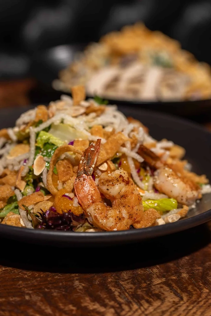 Shrimp salad with lettuce, cabbage, noodles, oranges, wontons, and almonds.