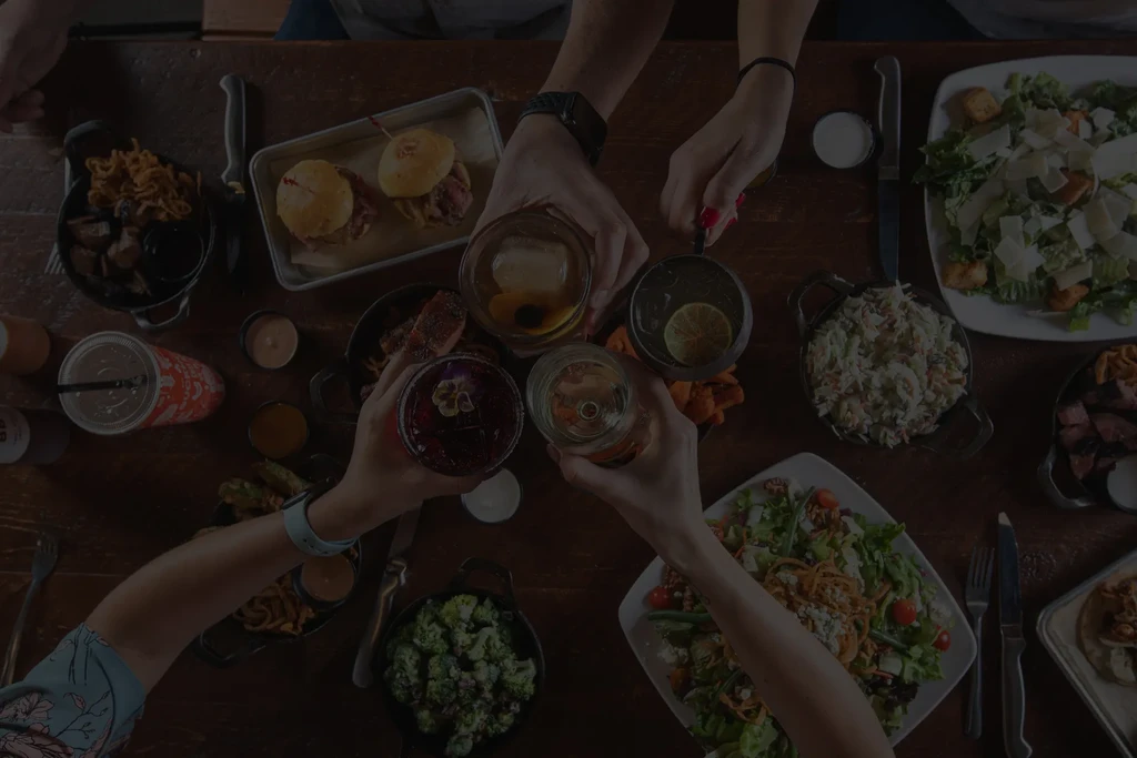 Overhead shot of many hands toasting over a laden dining table.