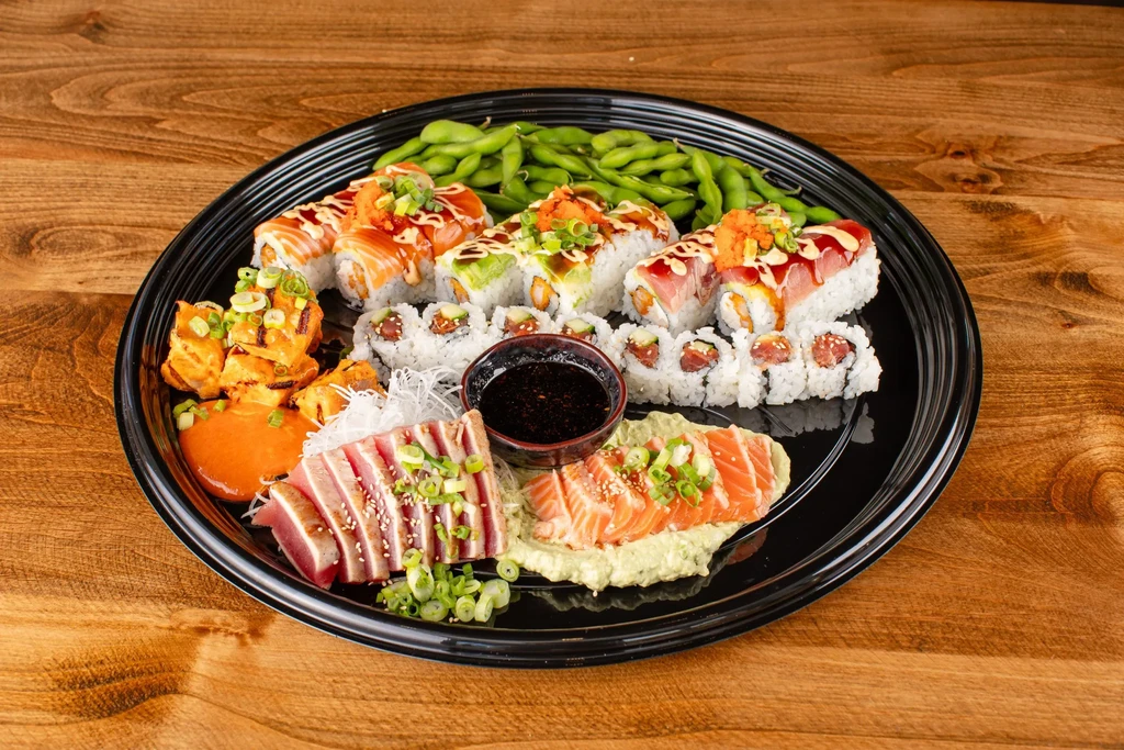 Platter of sushi rolls, sashimi, edamame, and seared protein.