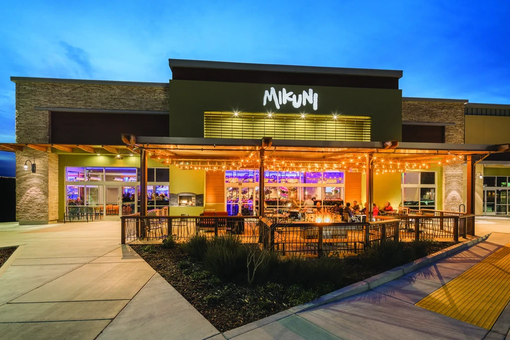 MIKUNI restaurant exterior, lively lit patio at dusk with patrons.