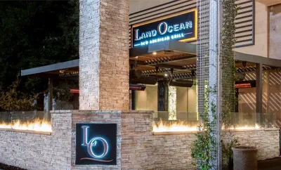 Land Ocean restaurant exterior at night, stone, prominent signs, fire pits.