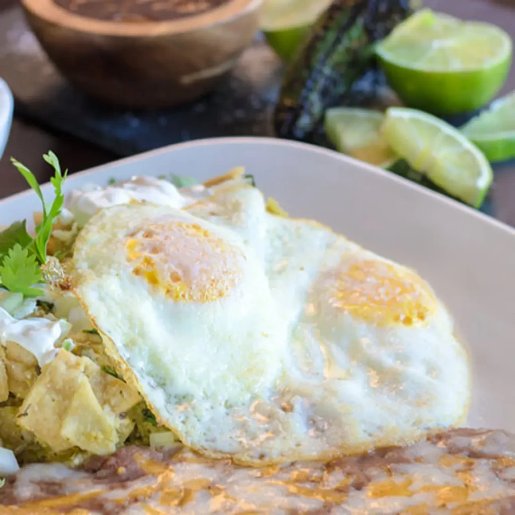 Chilaquiles topped with two sunny-side-up eggs, beans, and cilantro.
