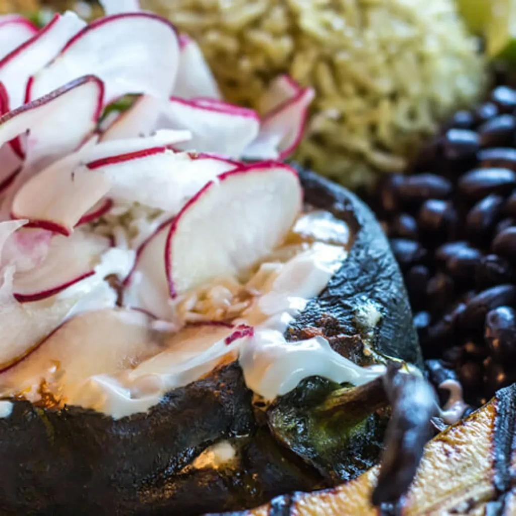 Roasted green pepper topped with cream, radishes, rice, and beans.