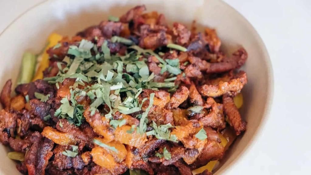 Bowl of chopped reddish-brown meat, orange peppers, and green cilantro.