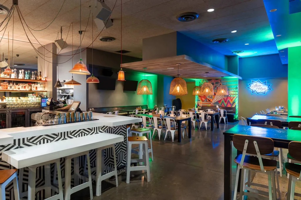 Vibrant modern restaurant interior with geometric bar and colorful lighting.