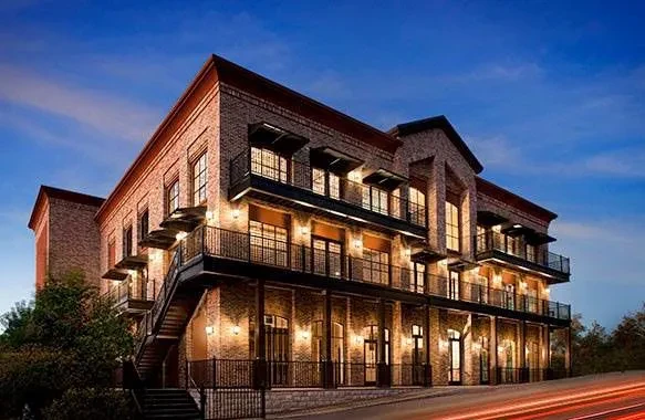 Brick building with illuminated windows, balconies, and long-exposure vehicle light trails.